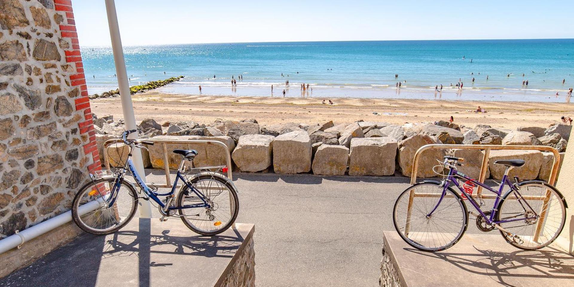Deux vélos garés près d'une plage avec des gens nageant dans l'eau