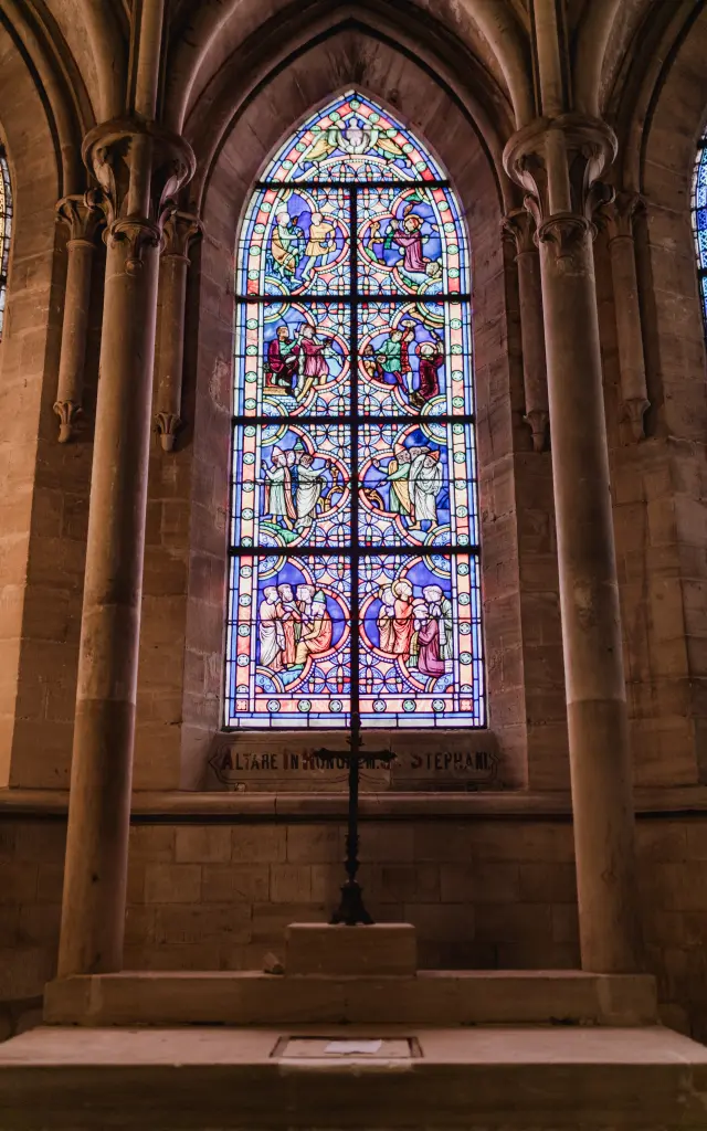 Colorful stained glass depicting religious scenes framed by stone columns in a church