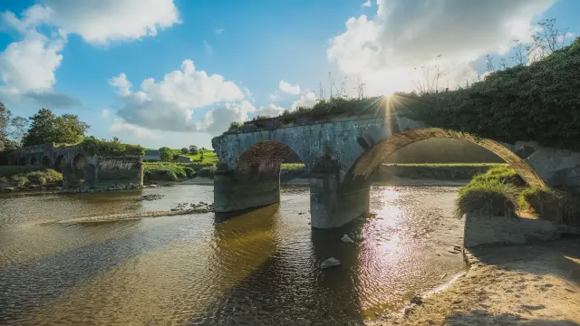 Stone arch bridge over a river with surrounding vegetation