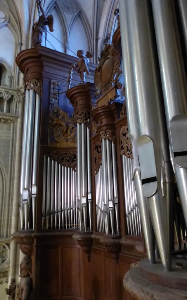 Orgue ancien dans une église gothique avec des vitraux colorés et des piliers