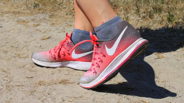 Pied d’une personne portant une sandale rouge à semelle blanche, assis sur un transat noir