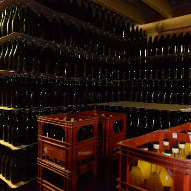 Rayonnages remplis de bouteilles de cidre et de caisses de bouteilles