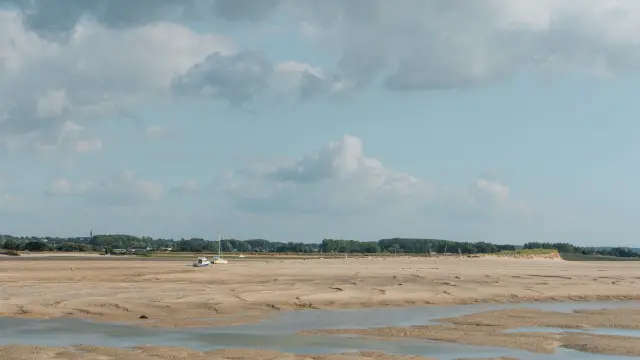 Sandstrand mit Wasserpfützen und bewölktem Himmel
