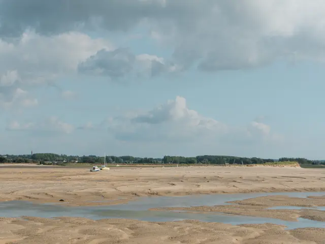 Sandy beach with water puddles and a cloudy sky
