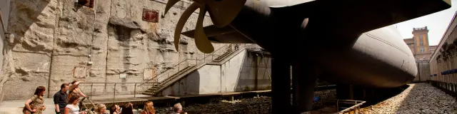 Gruppe von Menschen, die eine Schiffsschraube in einem Museum besichtigen