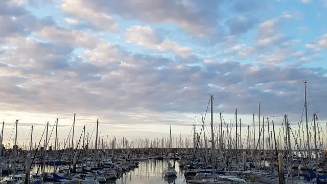 Boote im Hafen mit Wolkenreflexionen auf dem Wasser
