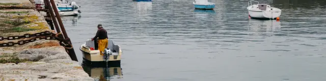 Ein Angler in einem gelben Anzug auf einem kleinen Boot