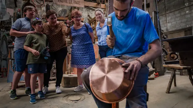Plusieurs personnes participant à un atelier de poterie autour d’une table avec des outils et des pièces en argile