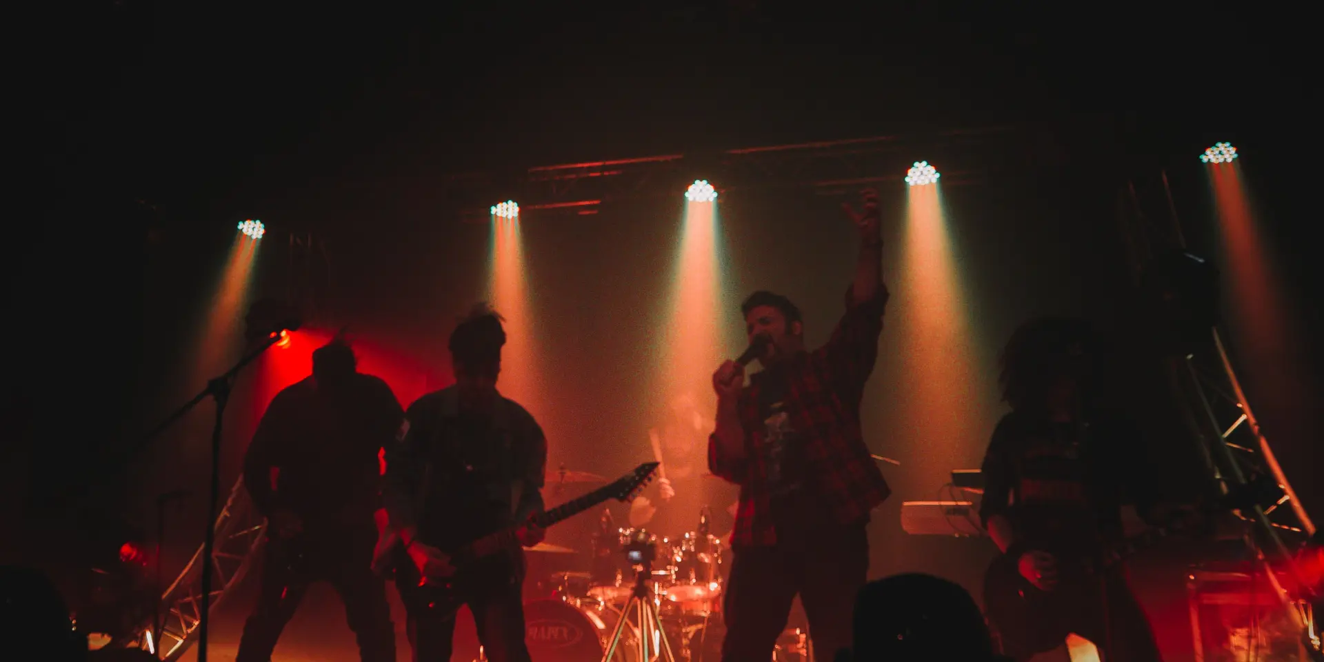 Groupe de musique jouant sur scène avec des projecteurs rouges