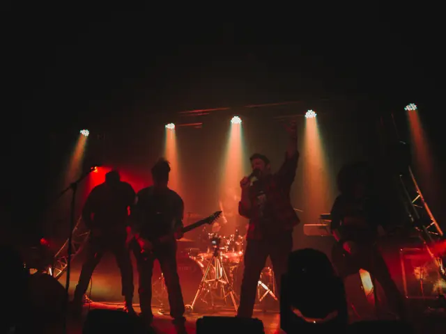 Groupe de musique jouant sur scène avec des projecteurs rouges