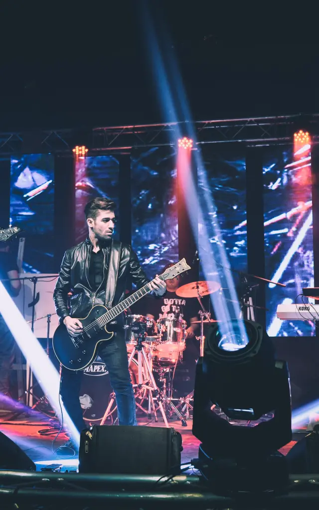 Groupe de rock jouant sur scène avec des guitares électriques sous des lumières colorées