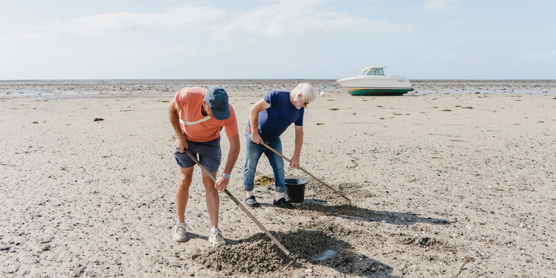 Zwei Personen sammeln Müll am Strand
