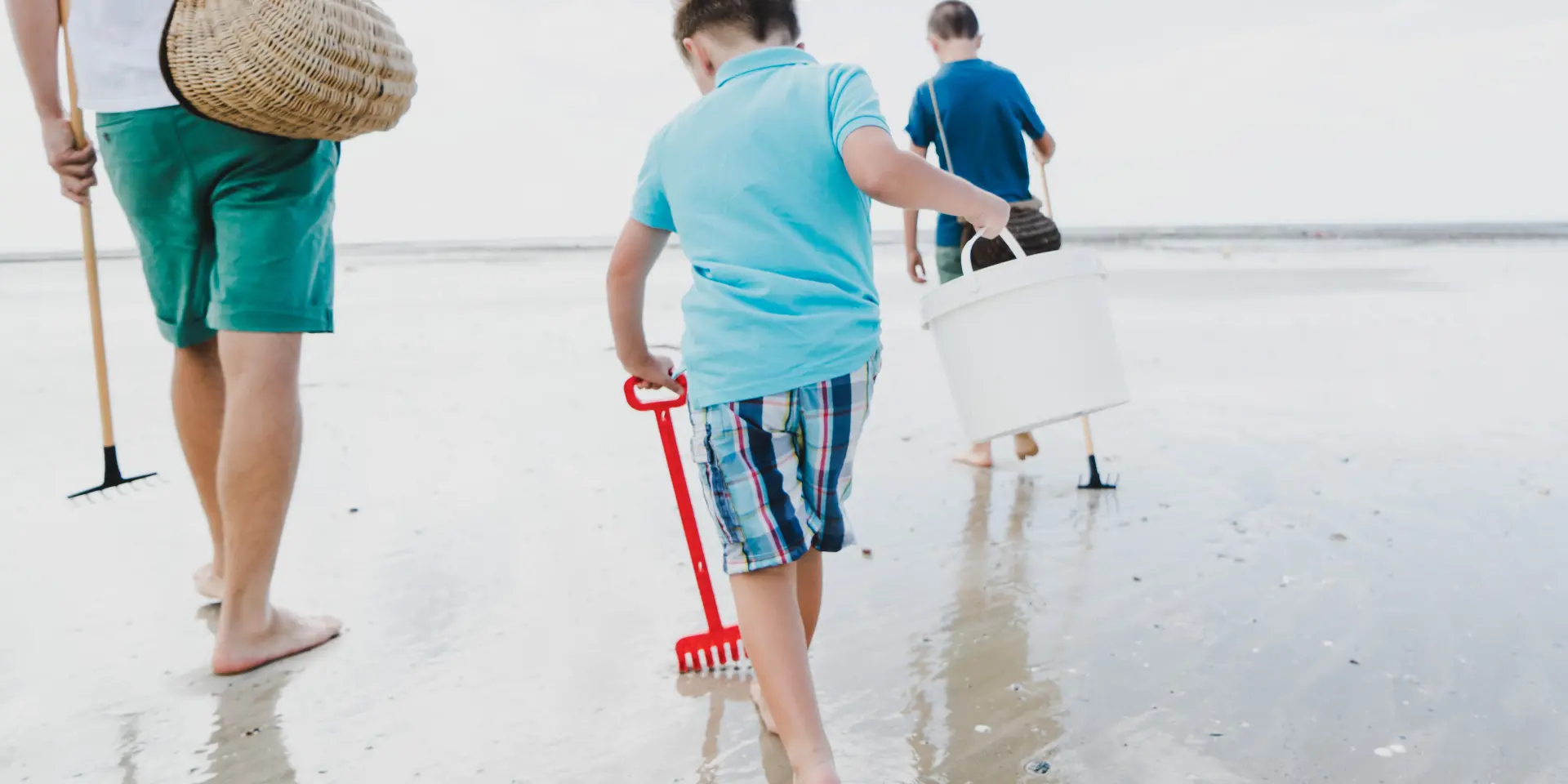 Enfants marchent sur la plage avec des seaux et des pelles pour la pêche à pied à Agon Coutainville