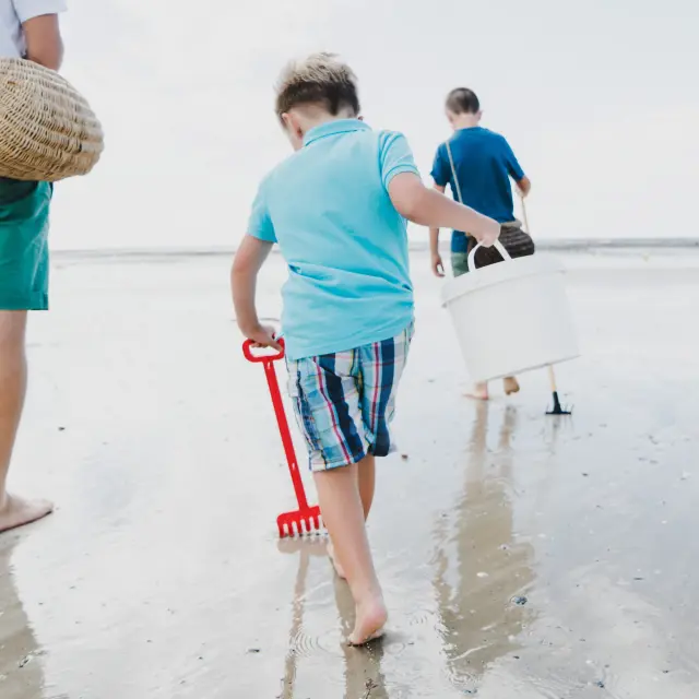 Enfants marchent sur la plage avec des seaux et des pelles pour la pêche à pied à Agon Coutainville