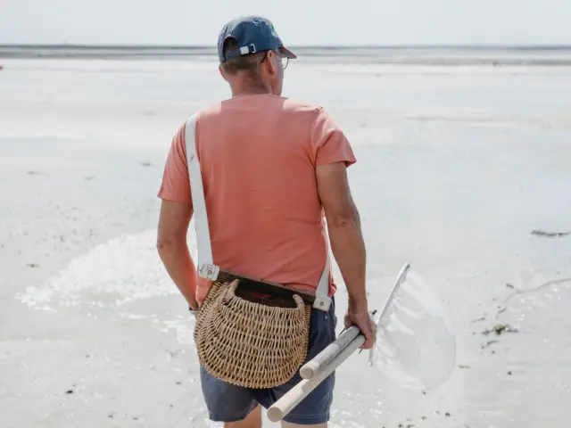 Homme marchant sur la plage avec un filet de pêche à Agon Coutainville