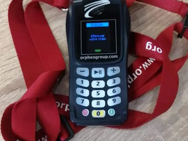 Télécommande bleue avec pavé numérique et écran d'affichage, posée sur un coussin rouge