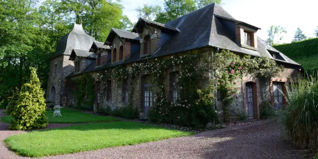 Bâtiment en pierre avec un toit en ardoise et des vignes grimpantes au château de Cerisy La Salle