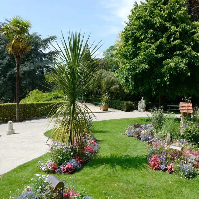 Allée en béton bordée de plantes tropicales et de fleurs colorées dans un jardin en bord de mer