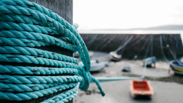 Gros plan d'une corde bleue enroulée autour d'un poteau sur un quai à Port Racine