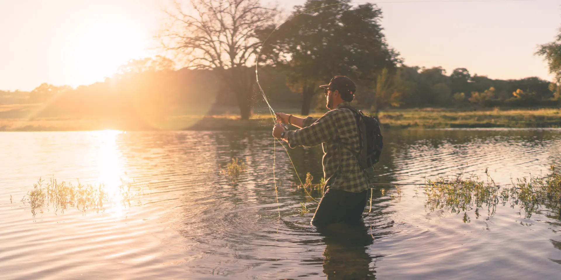 Personne debout sur un ponton au coucher du soleil, avec des voiliers amarrés en arrière-plan