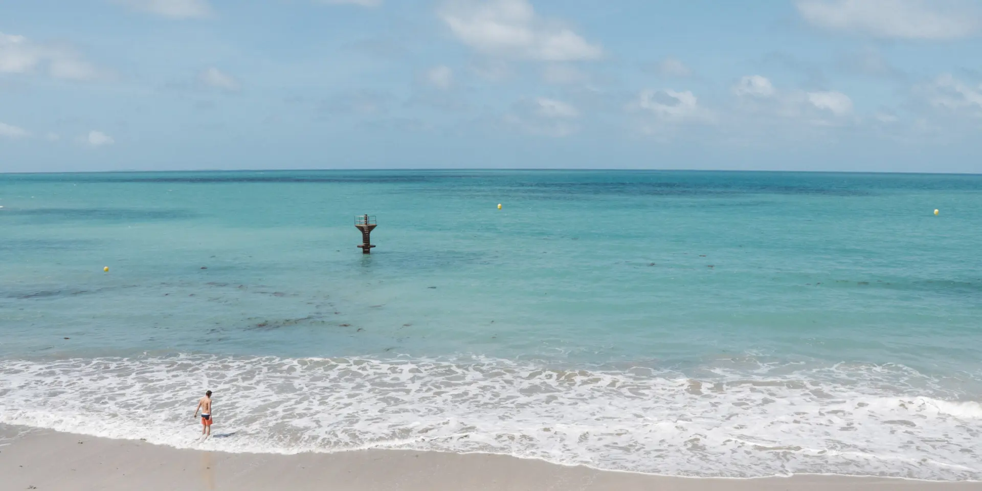 Two people on a fine sandy beach with a turquoise sea
