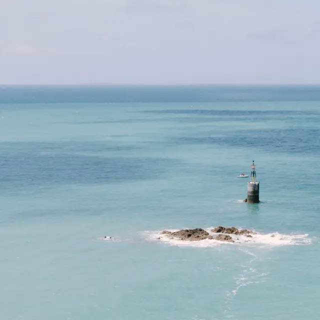 Lighthouse on a small rocky island in the middle of the turquoise sea