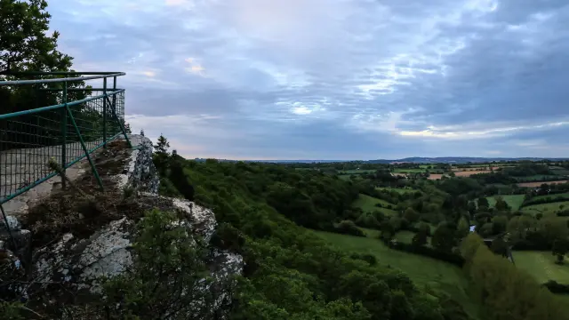 Panoramablick über ein grünes Tal mit bewölktem Himmel