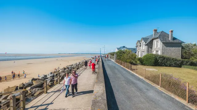 Personnes marchant le long d'une promenade en bord de mer à Hauteville sur Mer