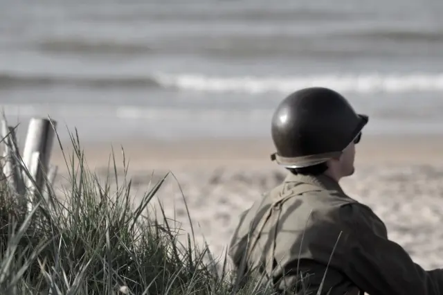 Un soldat en uniforme militaire regarde la mer
