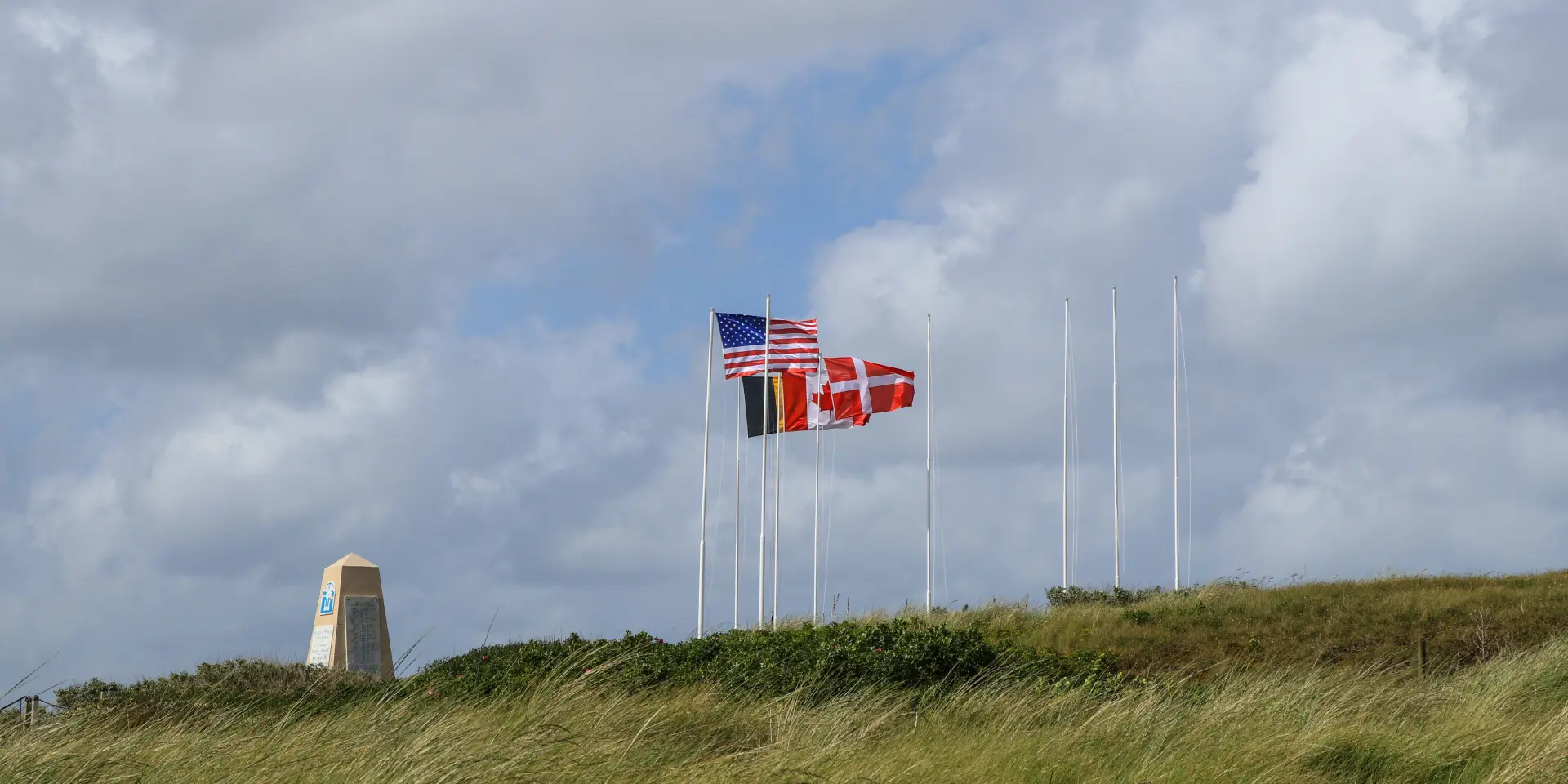 Trois drapeaux flottant avec un ciel nuageux en arrière-plan