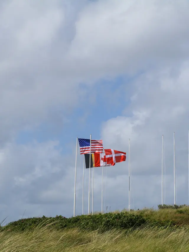 Trois drapeaux flottant avec un ciel nuageux en arrière-plan