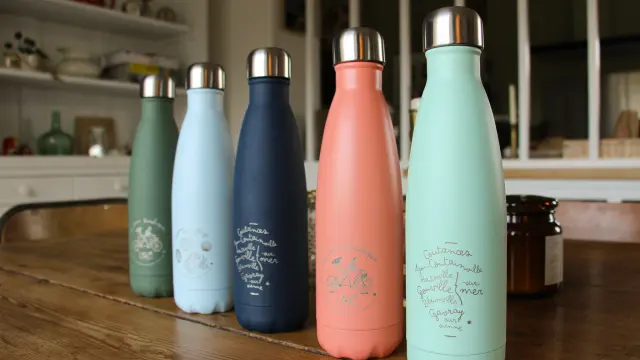 Cinq gourdes en métal de différentes couleurs sur un comptoir de cuisine de la boutique de Coutances Tourisme