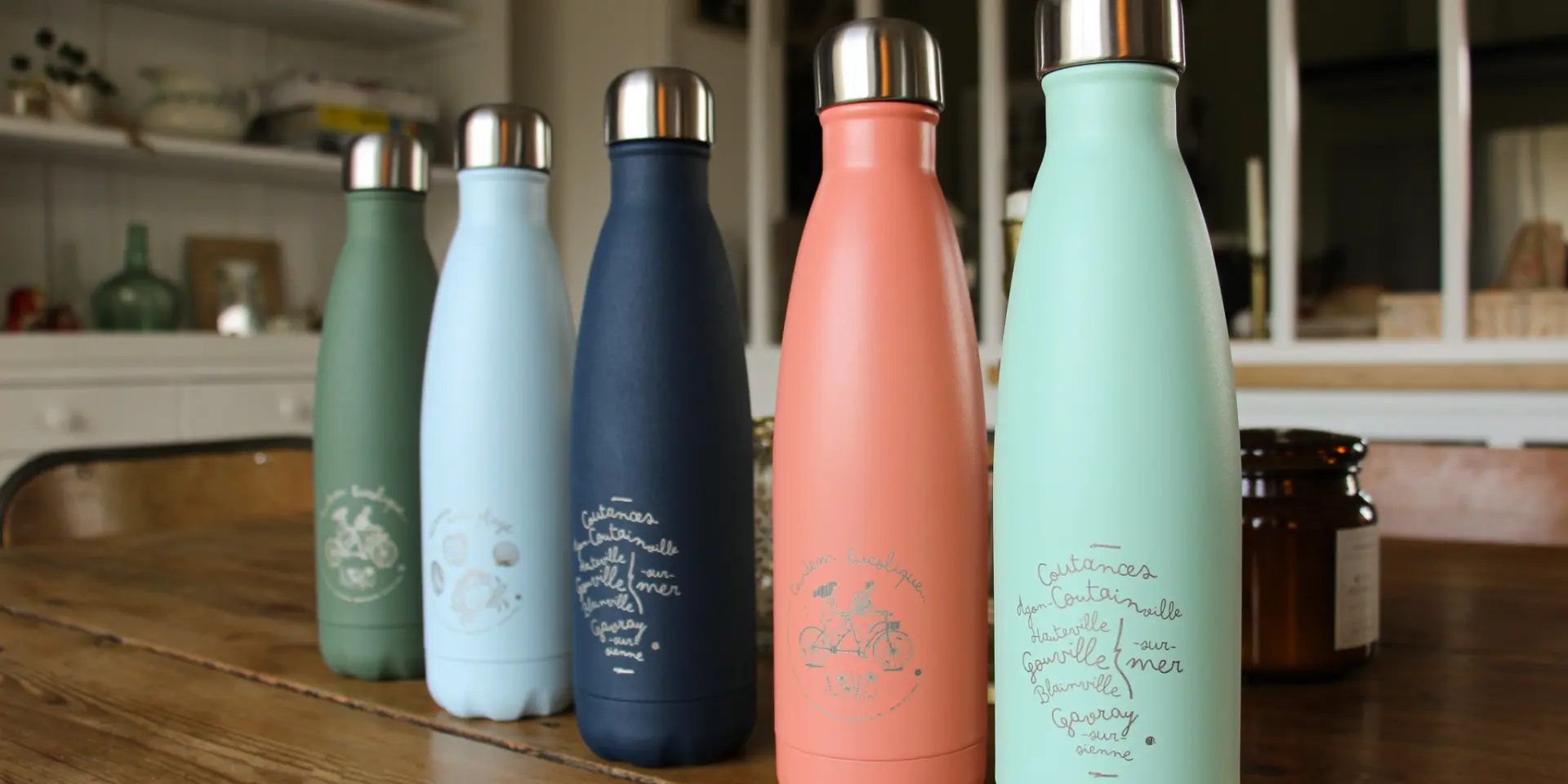 Cinq gourdes en métal de différentes couleurs sur un comptoir de cuisine de la boutique de Coutances Tourisme