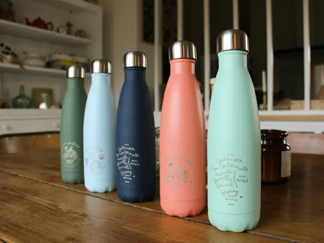 Cinq gourdes en métal de différentes couleurs sur un comptoir de cuisine de la boutique de Coutances Tourisme