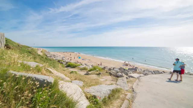 Deux personnes marchent sur un chemin de plage avec vue sur la mer