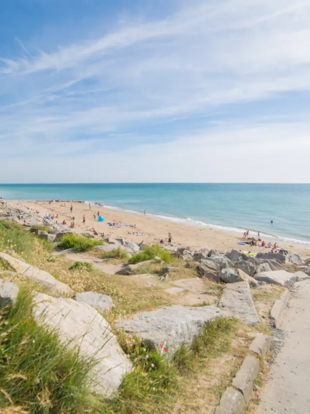 Two people walking on a beach path with a view of the sea