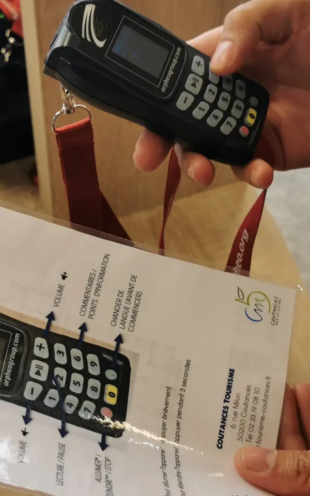 Une personne tient un audio-guide et une notice d'utilisation