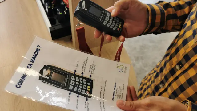 Une personne tient un audio-guide et une notice d'utilisation