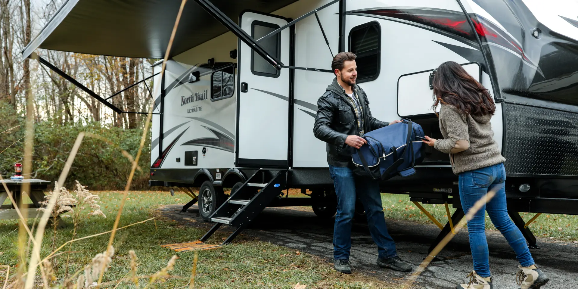 Un homme et une femme sortent un sac de voyage d'un camping-car