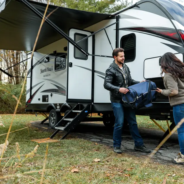 A man and a woman taking a travel bag out of a campervan