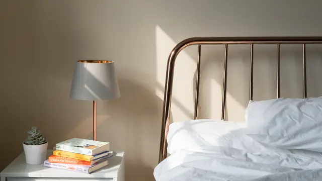 Chambre d'hôtel avec lit double, table de chevet, lampe, fenêtre et vue sur un bâtiment extérieur