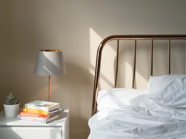 Lit avec une tête de lit en métal et une lampe de chevet à côté d'une pile de livres