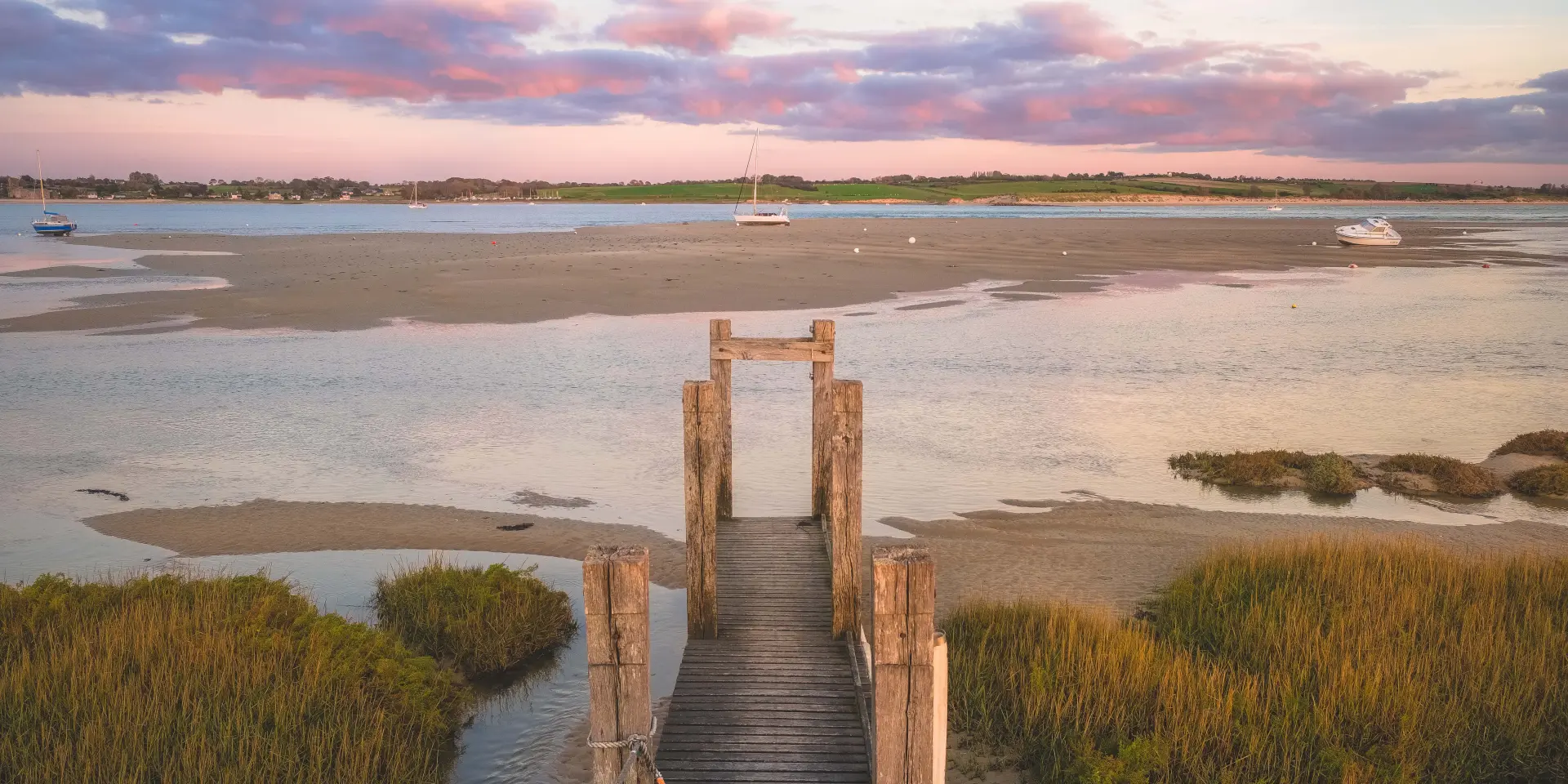 Salt marsh landscape at sunset with wooden posts and water stretches