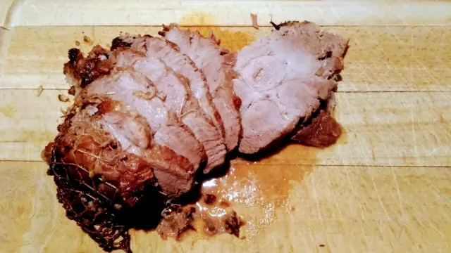 Un rôti de porccoupé en tranches sur une planche à découper en bois