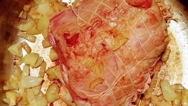 Un rôti de porc avec des oignons dans une cocotte en fonte