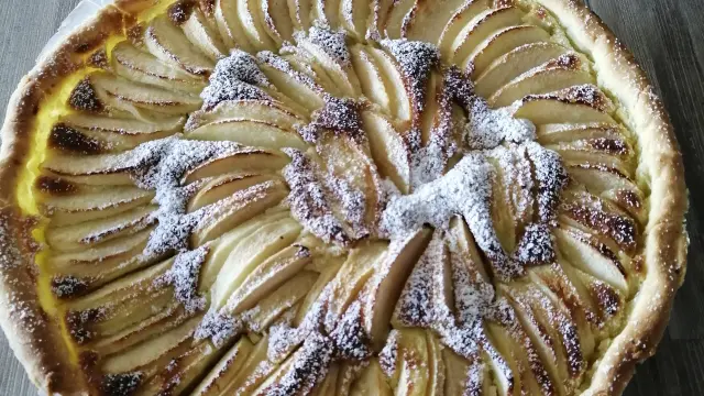 Tarte aux pommes avec une croûte dorée et des pommes disposées en rosace