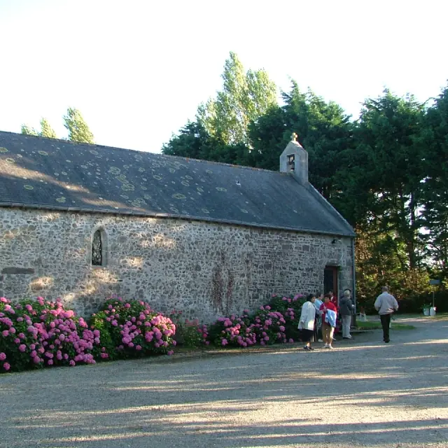 Steinkapelle mit rosa blühenden Sträuchern draußen