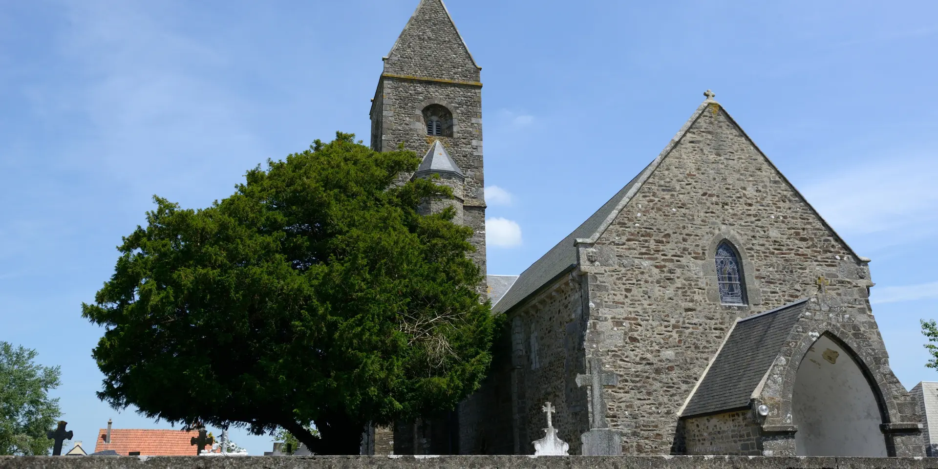 Steinkirche mit einem Glockenturm und einem Baum links