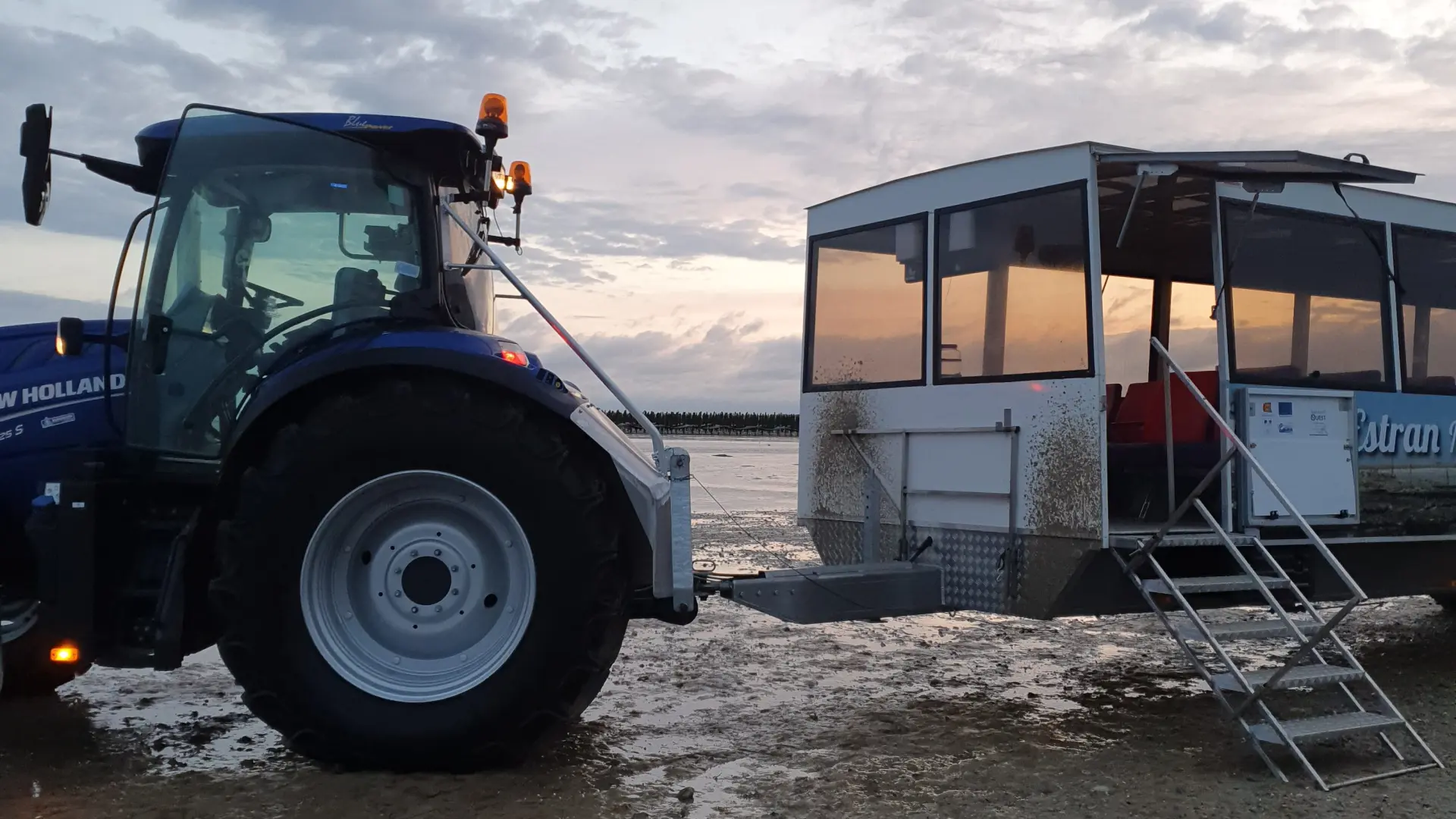 Un tracteur bleu et un bateau blanc sur une plage au coucher du soleil : La Balade d'Anton