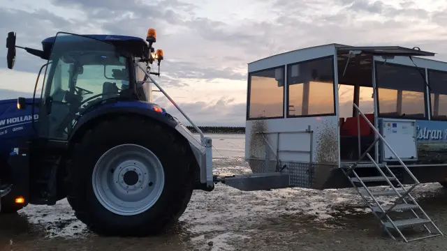 Un tracteur bleu et un bateau blanc sur une plage au coucher du soleil : La Balade d'Anton